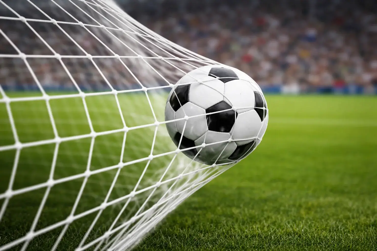 Voetbal die het net raakt bij een doelpunt in een verlicht stadion